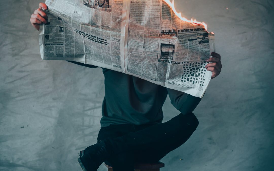 man holding newspaper which is on fire