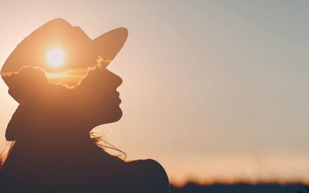 Silhouette of a woman with a hat and inside is a sunset representing stopping certain beliefs